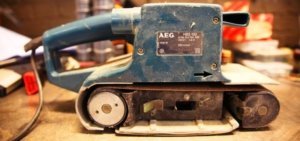 Ein Bandschleifer von der Seite fotografiert. Er ist blau und die Zeichen von AEG sind zu sehen.