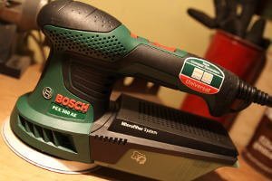 Ein niegelnagelneuer Exzenterfarbe der Firma Bosch befindet sich auf einem Tisch. Er ist Kabelgebunden und aus der grünen Kollektion.